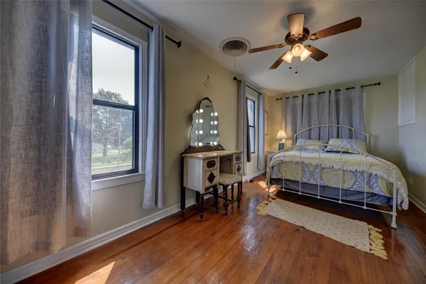 a bedroom with a bed and a large window with wooden floor