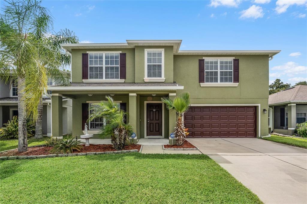 a view of a house with small yard plants and large tree