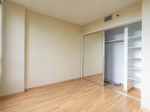 a view of an empty room with wooden floor and closet