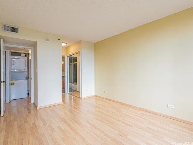 a view of an empty room with wooden floor and closet