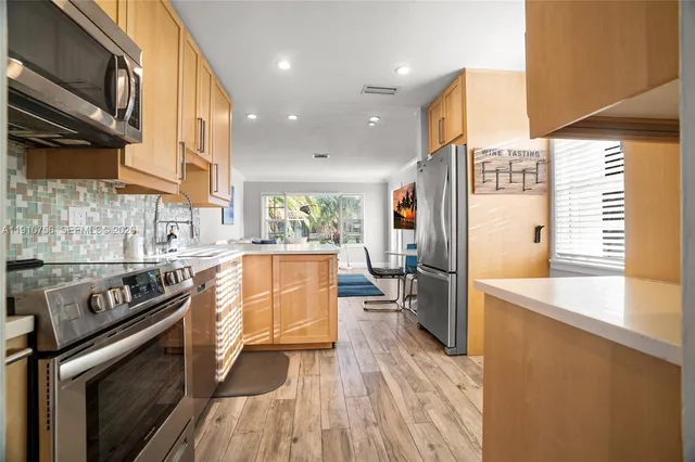 a kitchen with stainless steel appliances a stove a sink dishwasher a refrigerator white cabinets and wooden floor