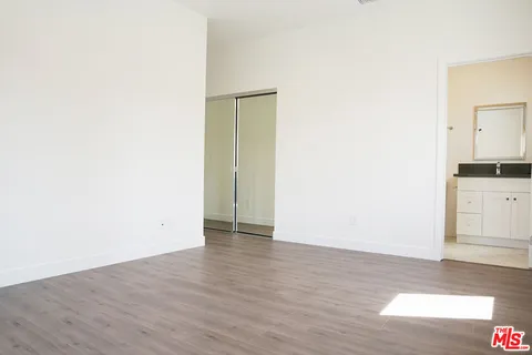 a view of an empty room with wooden floor and cabinets