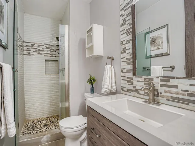 a bathroom with a granite countertop toilet a sink and a mirror