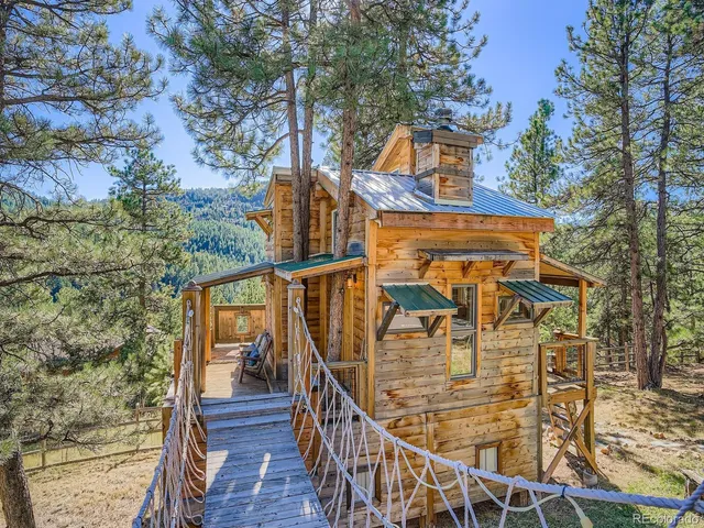 a view of a house with wooden fence and two trees