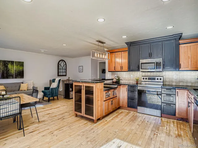 a kitchen with stainless steel appliances granite countertop a stove top oven a sink dishwasher a dining table and chairs with wooden floor