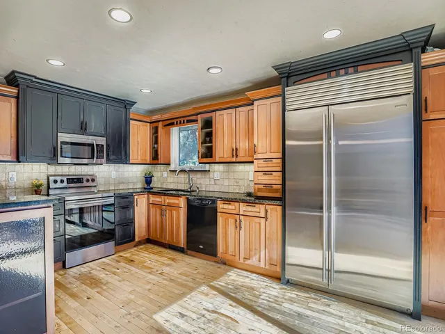a kitchen with stainless steel appliances granite countertop a refrigerator and a stove top oven