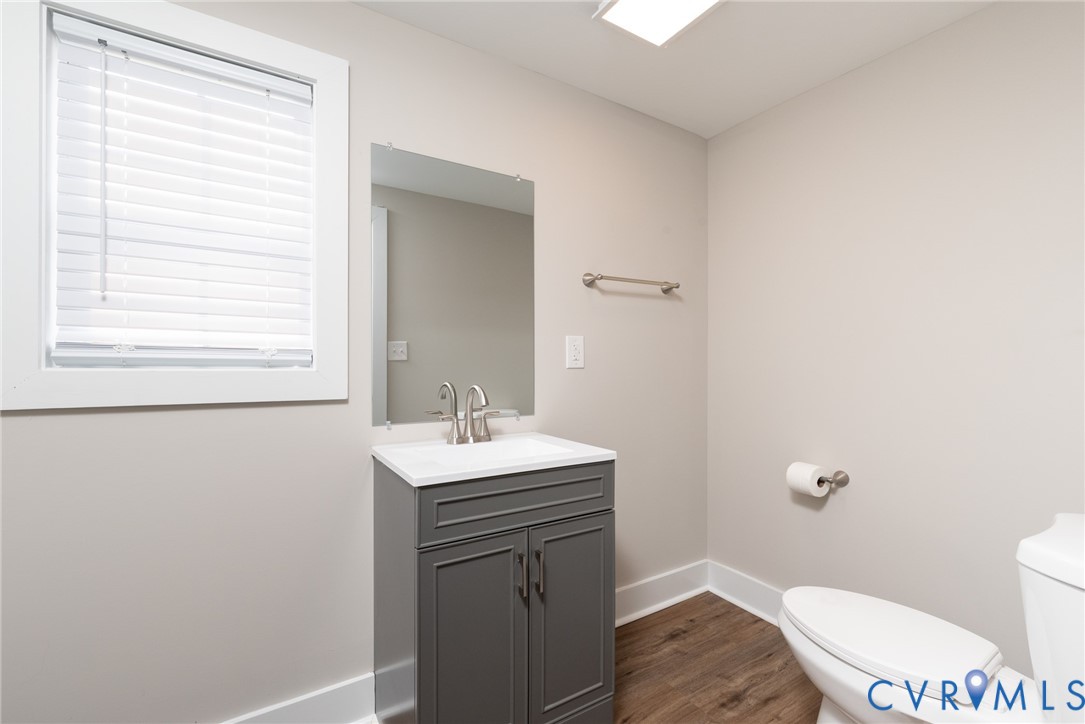 9800 Golf Course Drive Disputanta, VA 23842 - Photo 17 of 19 a bathroom with a toilet a sink a window and vanity