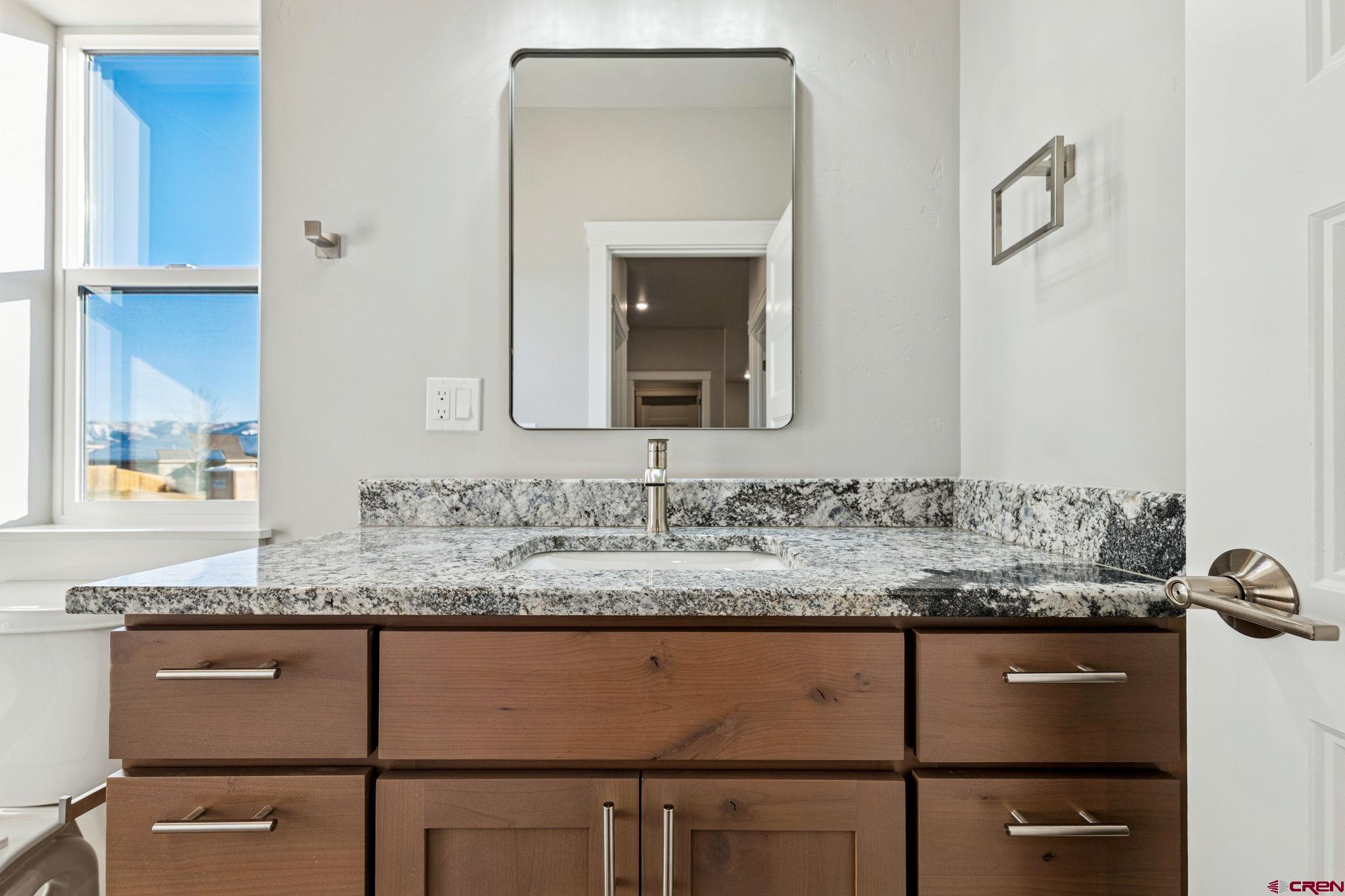 2223 Golf Course Lane Cortez, CO 81321 - Photo 15 of 26 a bathroom with a granite countertop sink and a mirror