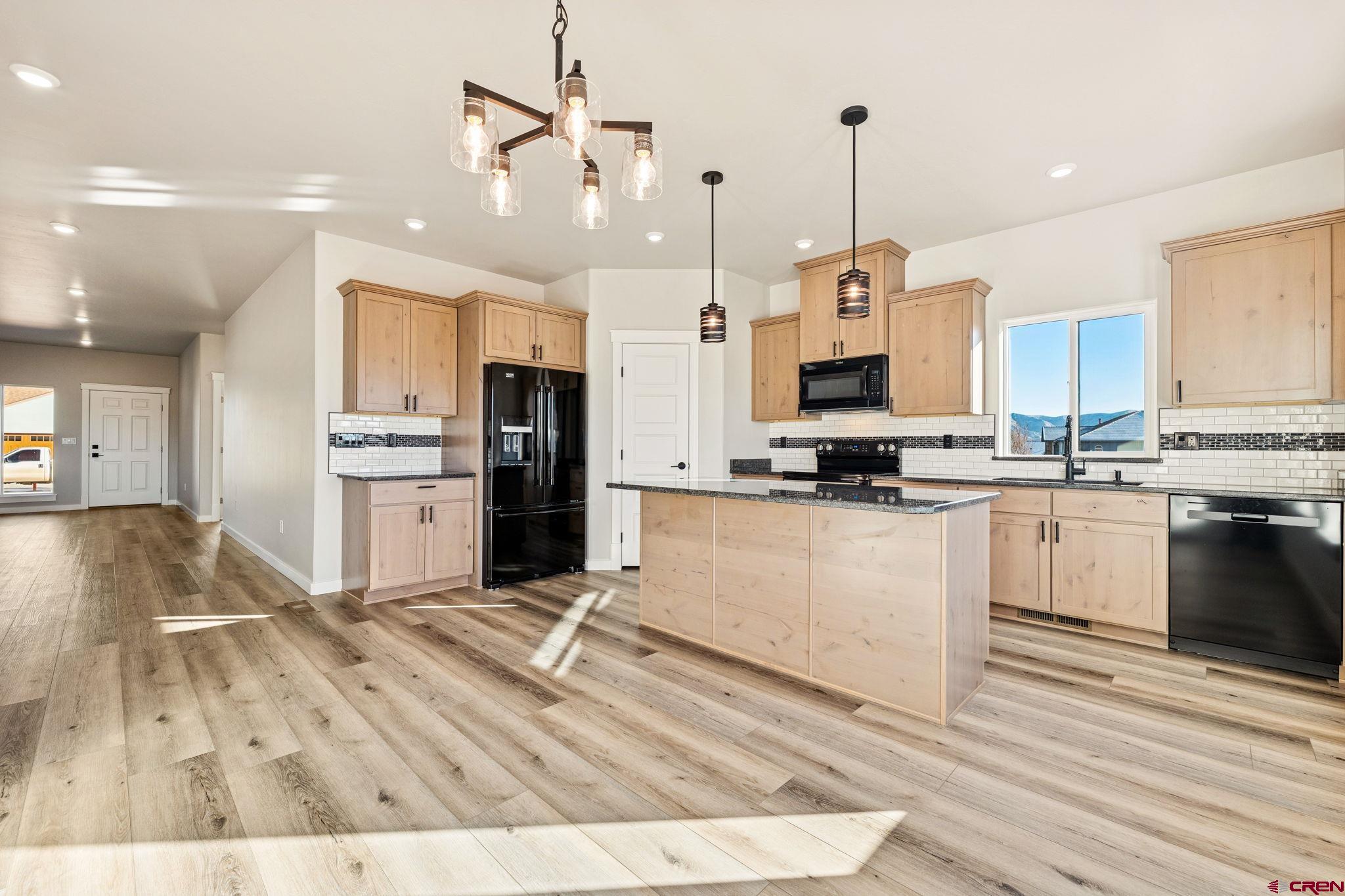 2223 Golf Course Lane Cortez, CO 81321 - Photo 4 of 26 a kitchen with stainless steel appliances kitchen island granite countertop a stove a sink a refrigerator and white cabinets with wooden floor