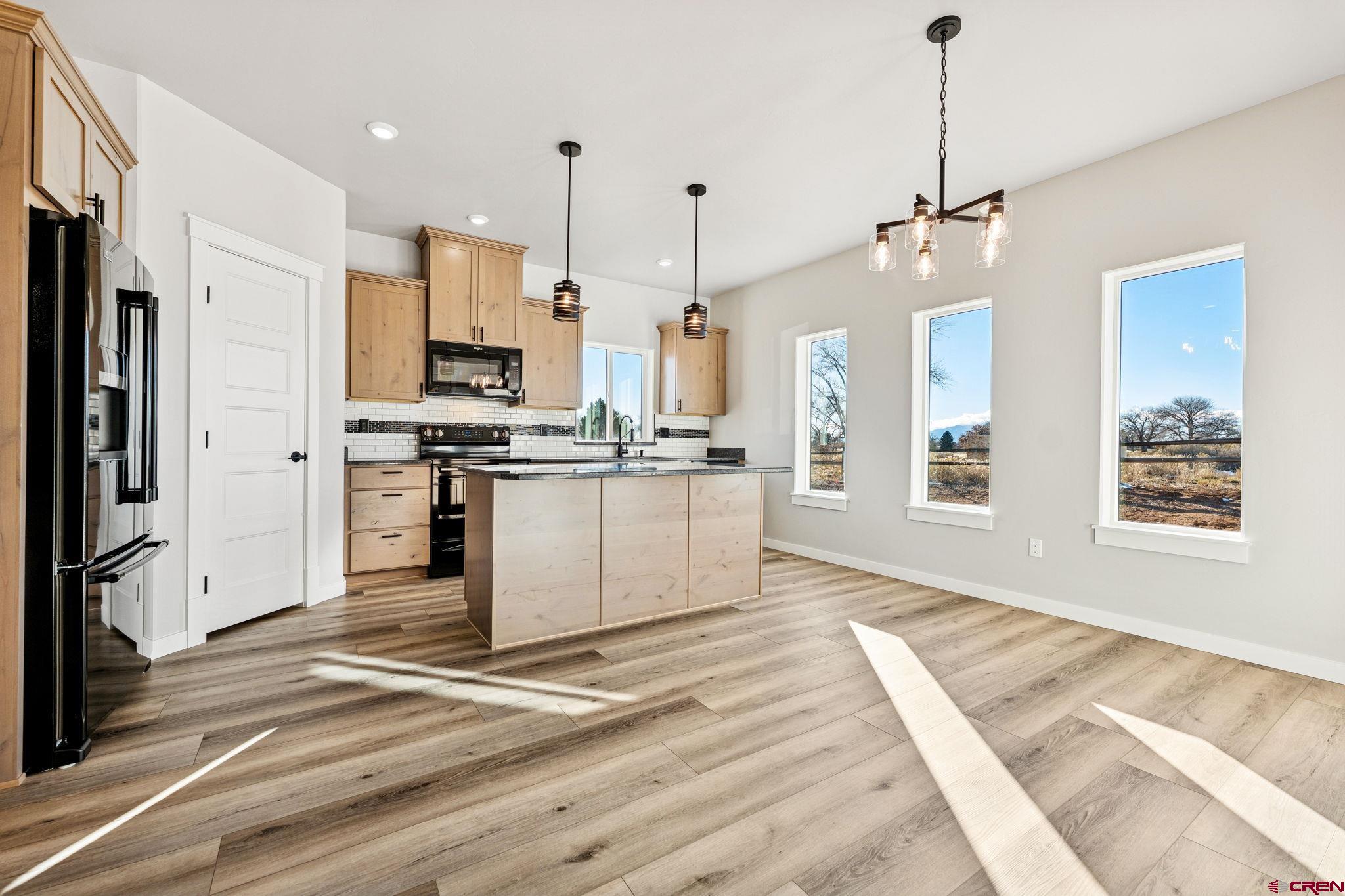 2223 Golf Course Lane Cortez, CO 81321 - Photo 5 of 26 a large kitchen with stainless steel appliances granite countertop a stove a refrigerator a sink dishwasher a oven with white cabinets and wooden floor
