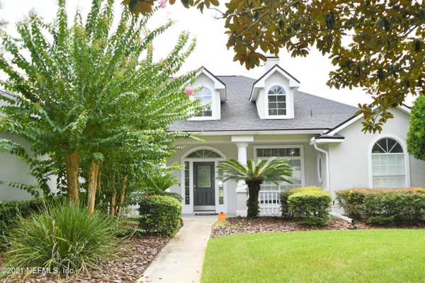 a front view of a house with a yard and trees