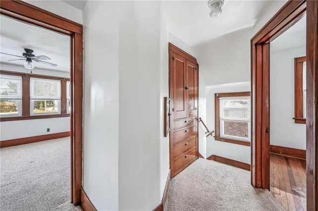 an empty room with chandelier fan and windows