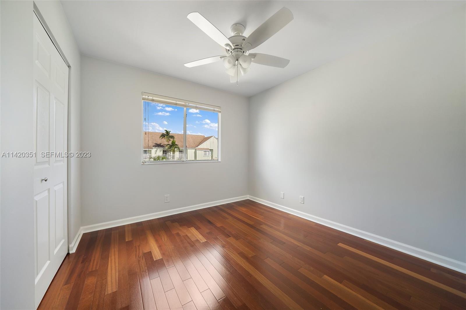 6351 Riverwalk Lane, Unit 4 Jupiter, FL 33458 - Photo 27 of 40 an empty room with wooden floor chandelier fan and windows