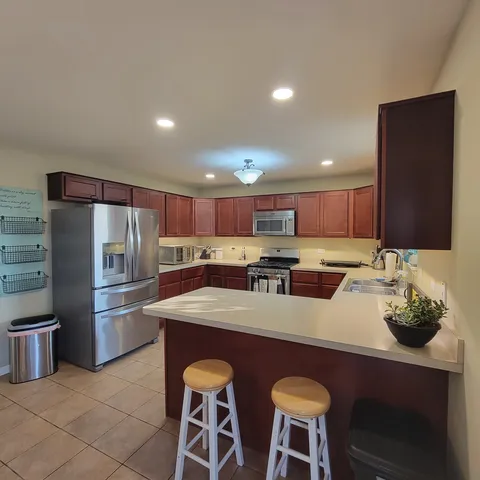 a kitchen with stainless steel appliances granite countertop a sink a stove a refrigerator cabinets and chairs
