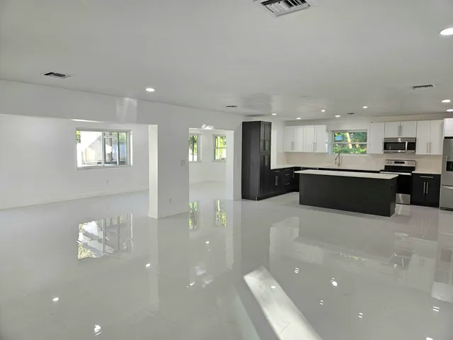 a large kitchen with stainless steel appliances a large counter top a stove and a refrigerator