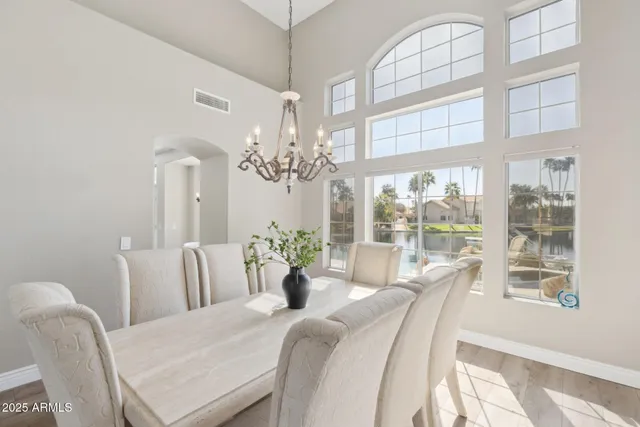 a dining room with wooden floor a chandelier a glass table and chairs