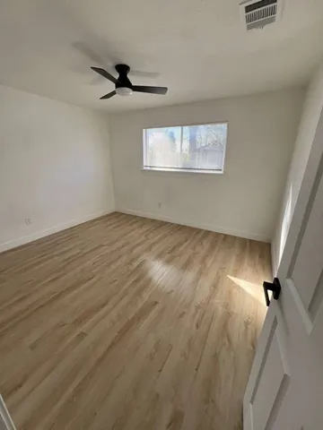 an empty room with wooden floor cabinet and windows