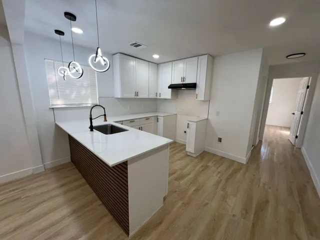 a kitchen with kitchen island sink stove and wooden floor