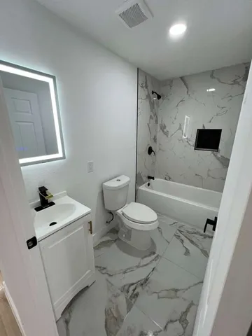 a white toilet sitting next to a bathroom sink and tub