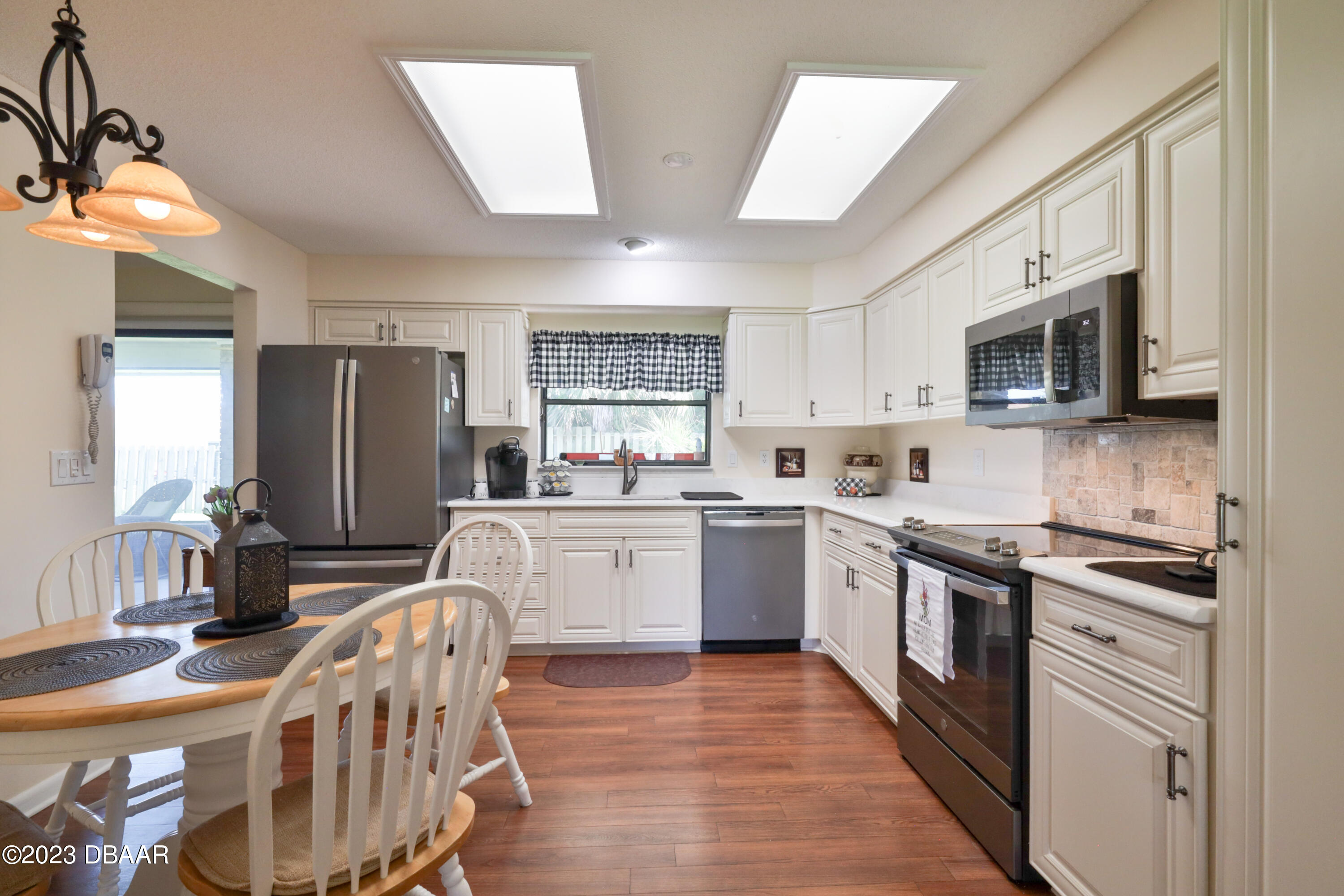 118 Sand Dunes Drive Ormond Beach, FL 32176 - Photo 19 of 46 a kitchen with stainless steel appliances granite countertop a stove top oven a sink dishwasher a refrigerator white cabinets and wooden floor