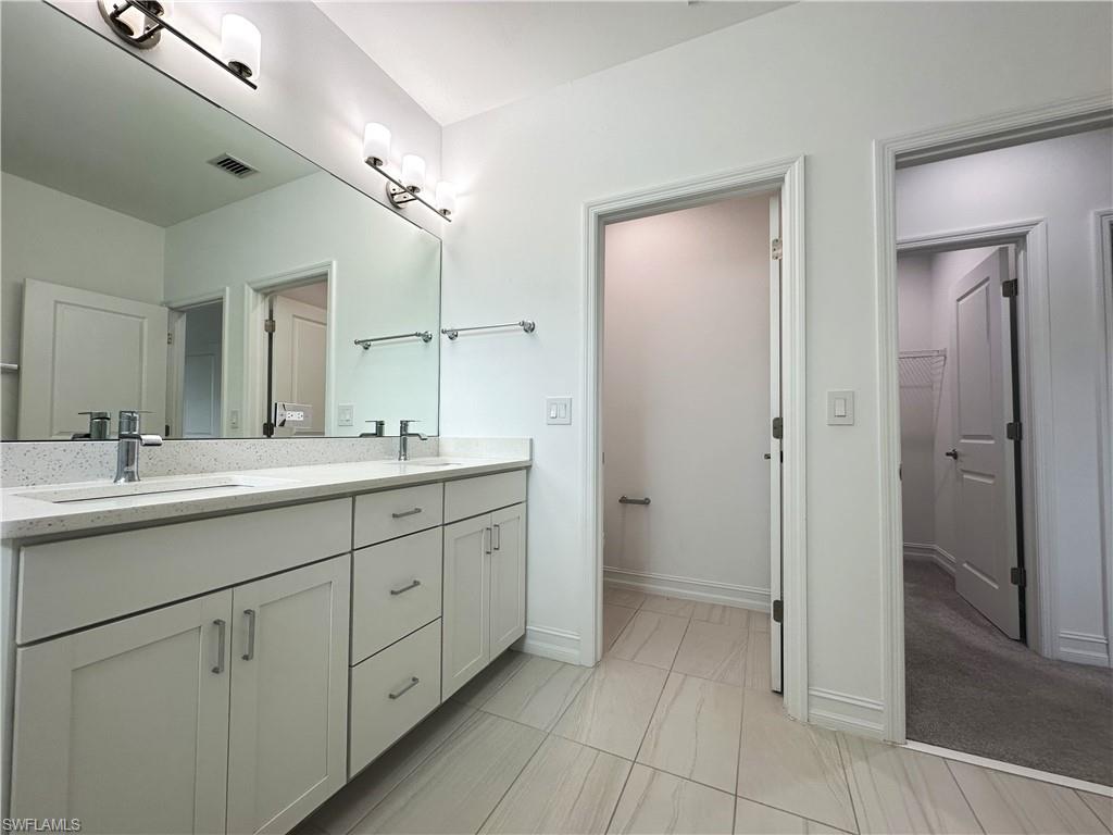 7509 Carnegie Way Naples, FL 34119 - Photo 18 of 33 a spacious bathroom with a double vanity sink a mirror and a shower