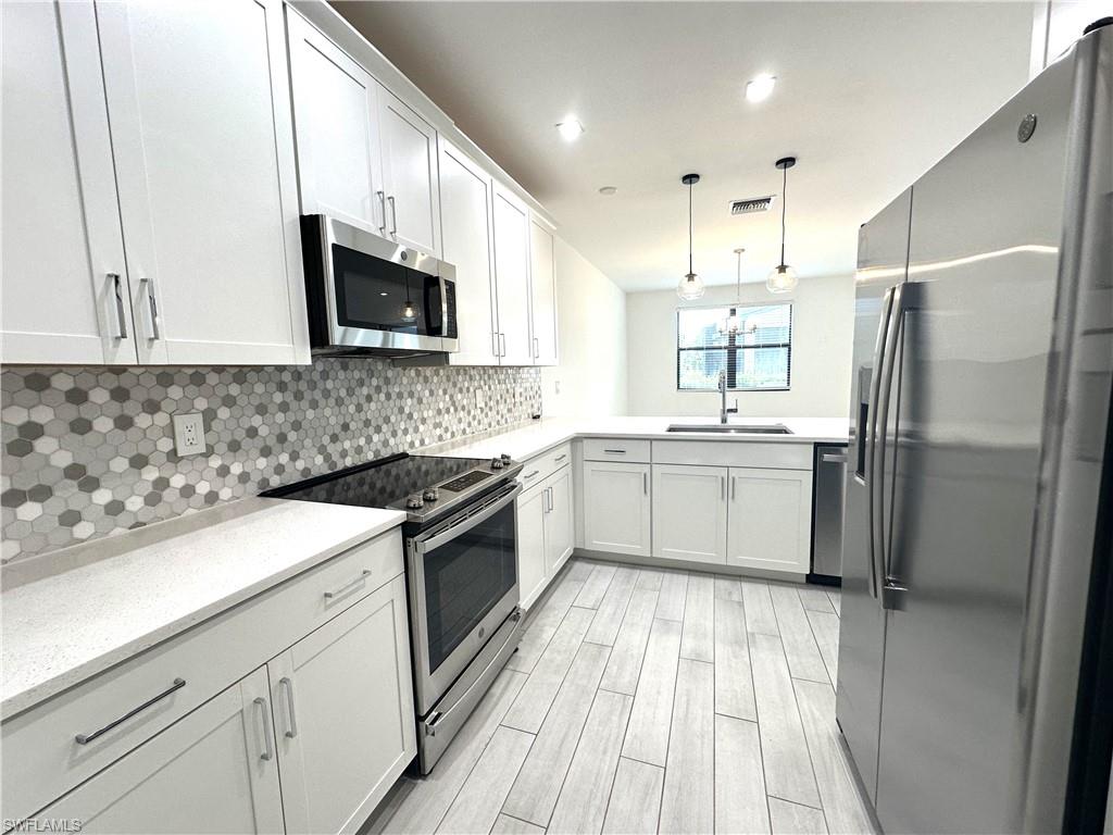 7509 Carnegie Way Naples, FL 34119 - Photo 3 of 33 a kitchen with a sink a counter top space stainless steel appliances and cabinets