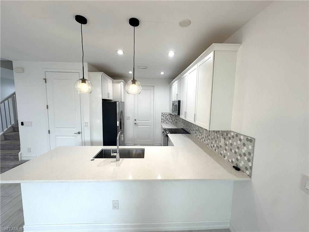 7509 Carnegie Way Naples, FL 34119 - Photo 5 of 33 a large kitchen with kitchen island a sink stainless steel appliances and a chandelier
