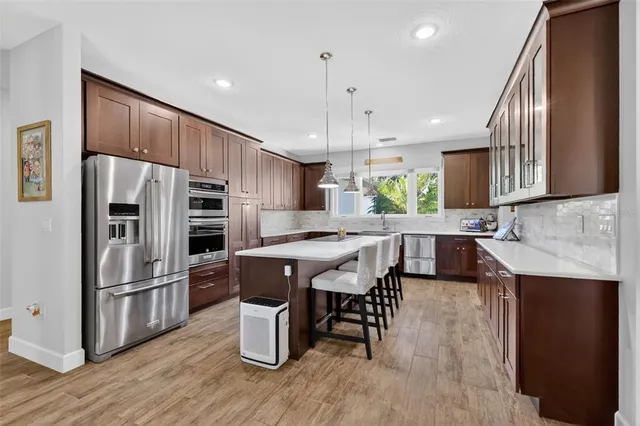 a large kitchen with granite countertop a large counter top stainless steel appliances and wooden floor