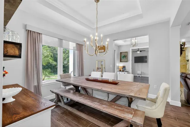 a dining room with wooden floor a chandelier a wooden table and chairs