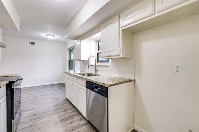 a kitchen with granite countertop a sink stove and cabinets