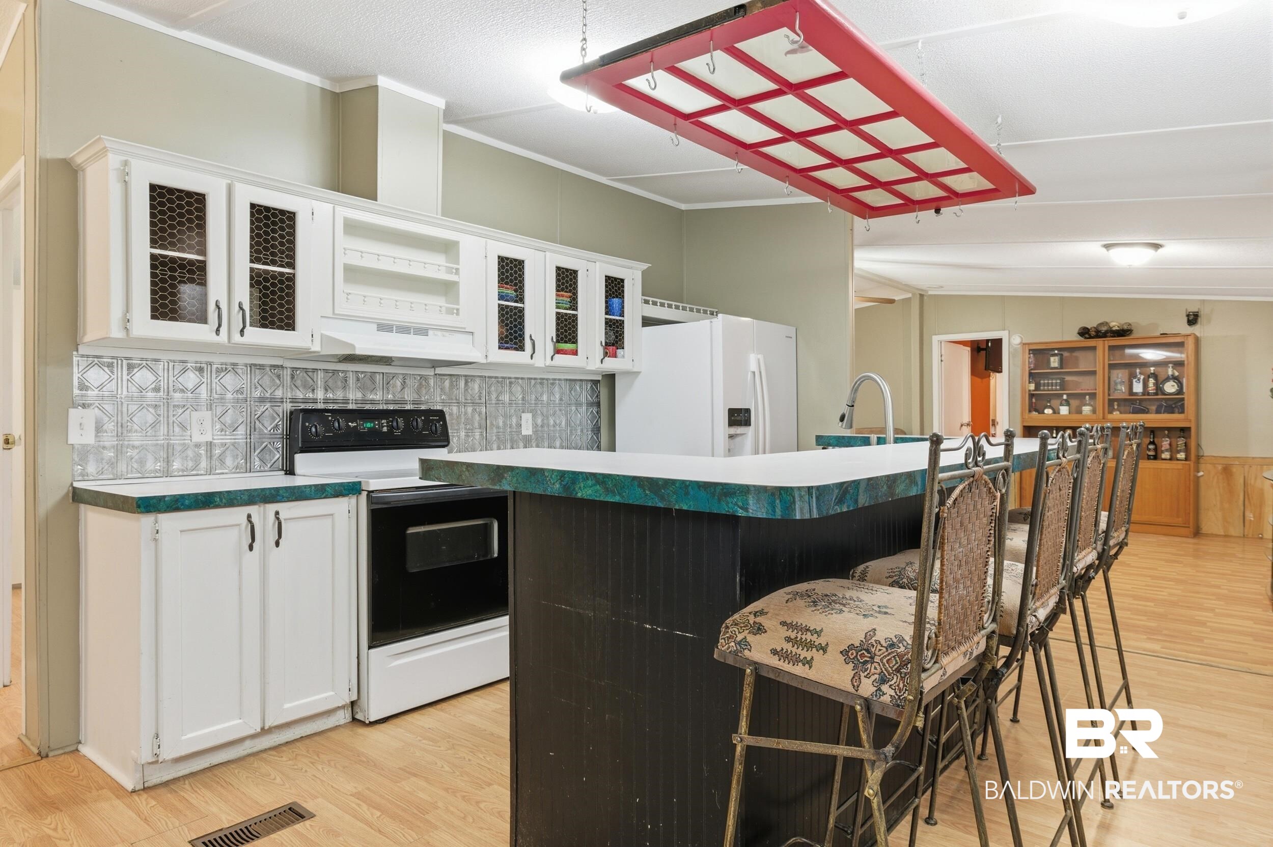 926 Tumbling Lane Atmore, AL 36502 - Photo 18 of 56 Kitchen featuring white cabinetry with some glass-front doors, a patterned metal backsplash, and a black and white electric range