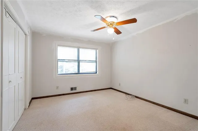 an empty room with ceiling fan and window