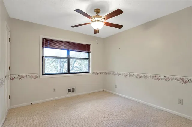 an empty room with a window and a ceiling fan