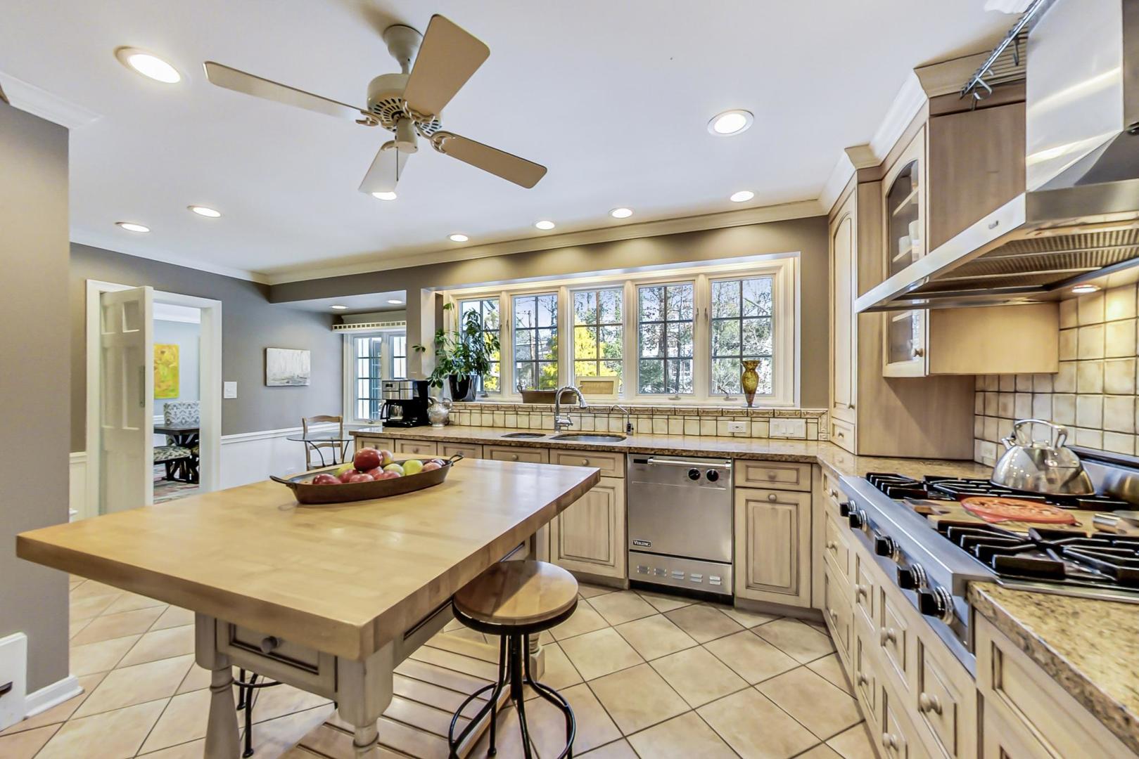 875 Fairview Road Highland Park, IL 60035 - Photo 7 of 32 a kitchen with a stove a sink a kitchen island with chairs and wooden floor