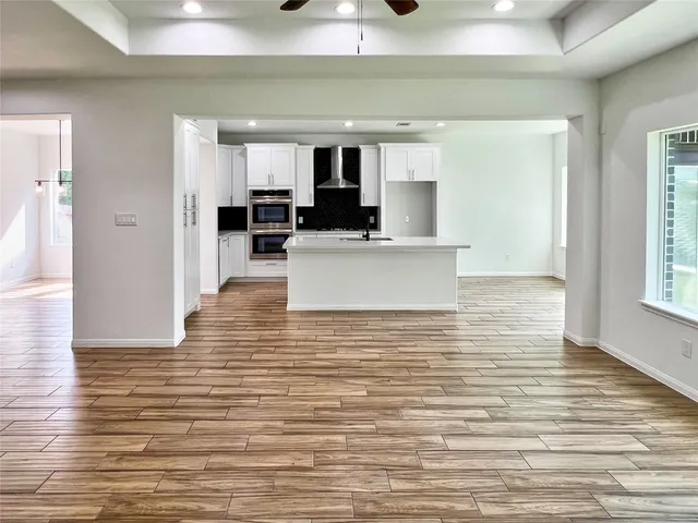 a view of living room with kitchen island stainless steel appliances wooden floor and window