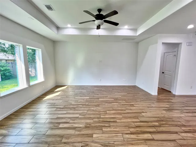 a view of empty room with wooden floor and fan