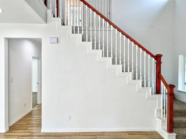 a view of staircase with lots of frames on wall and wooden floor