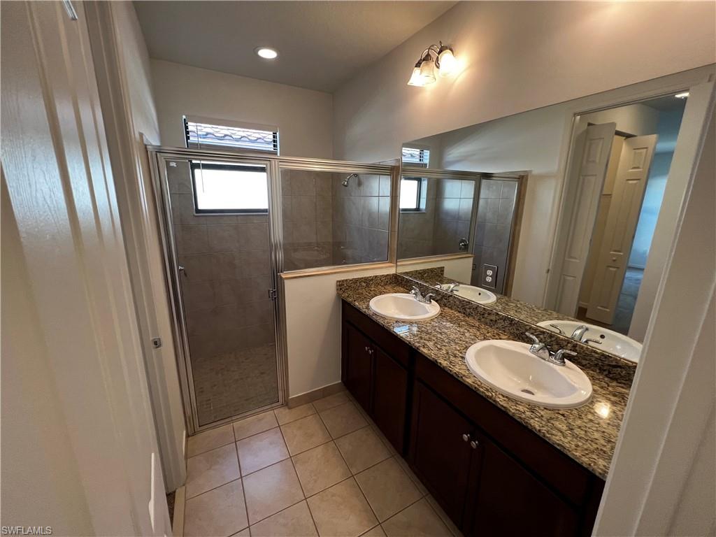 5542 Useppa Drive Ave Maria, FL 34142 - Photo 8 of 15 a bathroom with a granite countertop sink a mirror and a shower