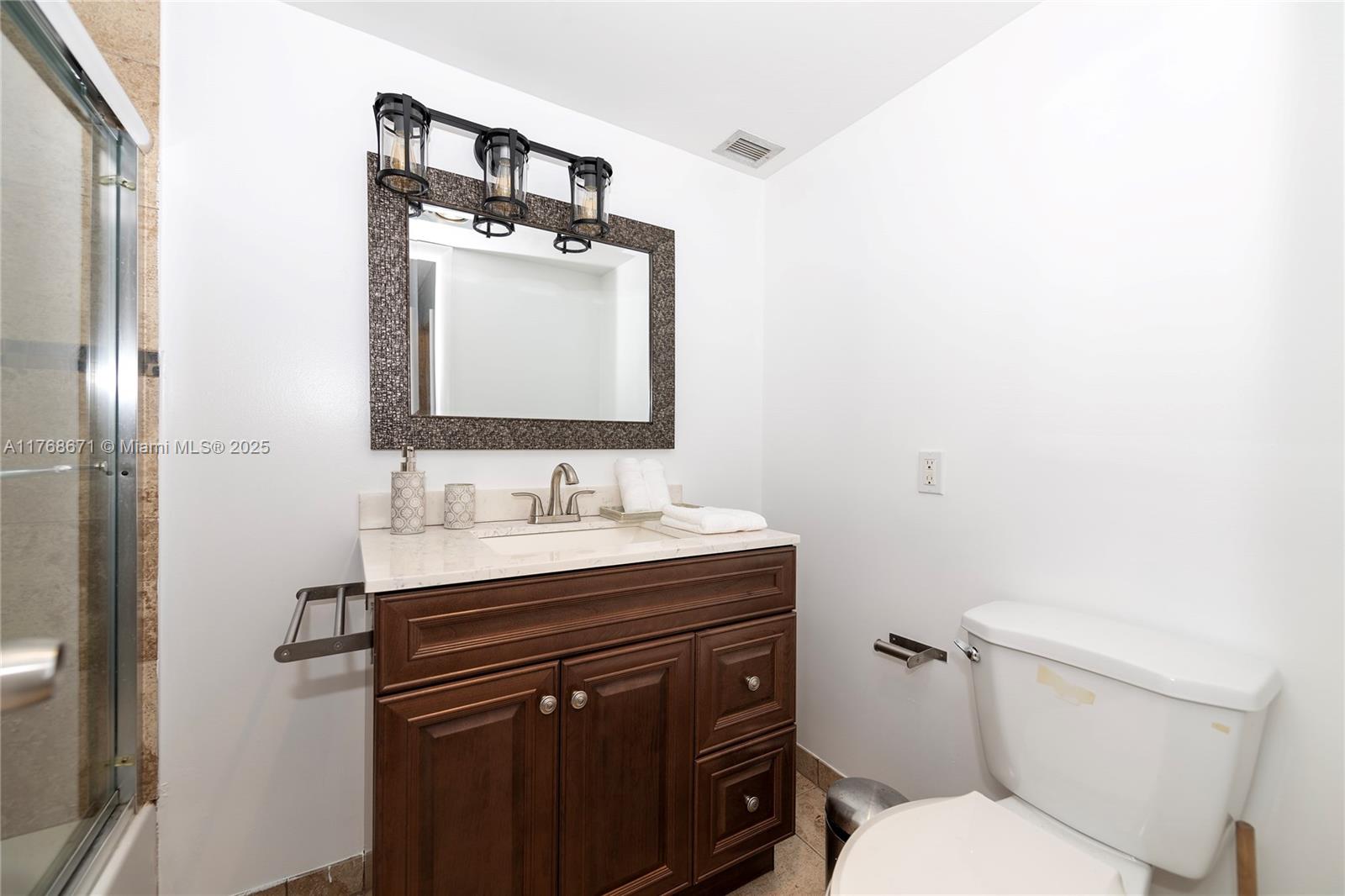 2750 Northeast 183rd Street, Unit 1207 Aventura, FL 33160 - Photo 19 of 21 a bathroom with a toilet sink vanity and mirror