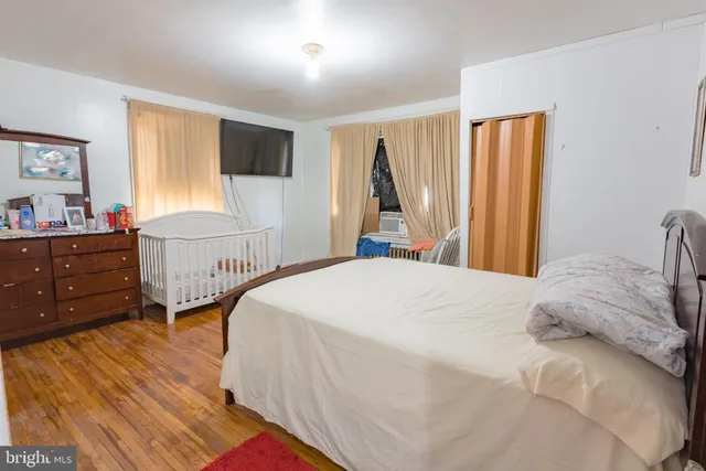 a bedroom with a bed and a flat tv screen on dresser