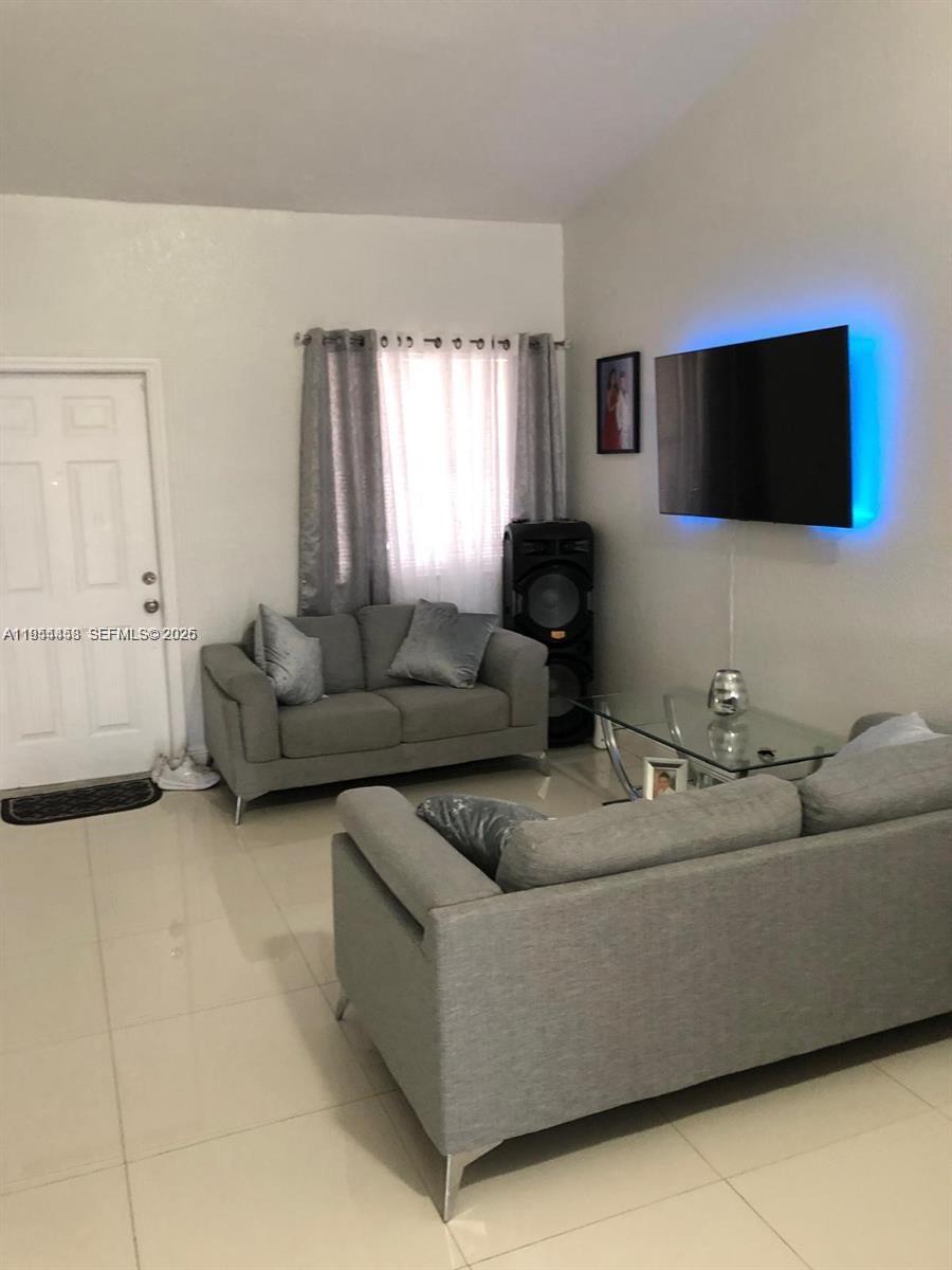 27 Northeast 13th Street, Unit 4 Homestead, FL 33030 - Photo 2 of 8 a living room with furniture and a flat screen tv