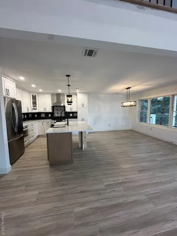 a living room with stainless steel appliances kitchen island granite countertop a large kitchen counter top space and a sink