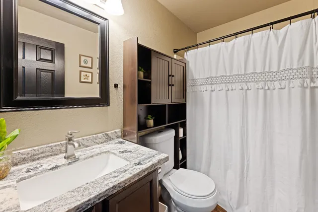 a bathroom with a granite countertop sink toilet and mirror