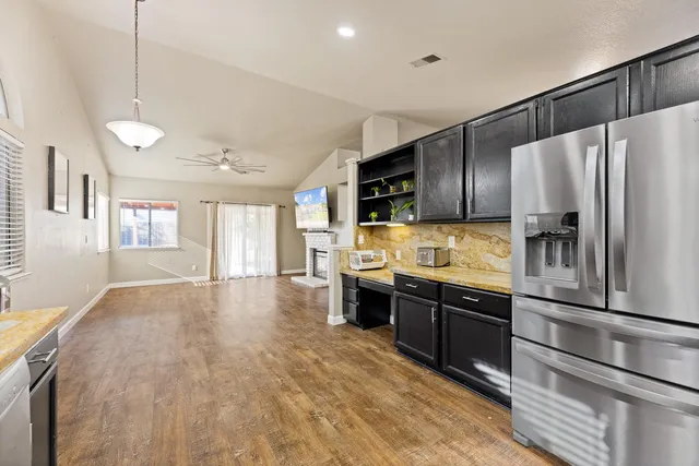 a kitchen with stainless steel appliances granite countertop a refrigerator a stove and a sink with cabinets