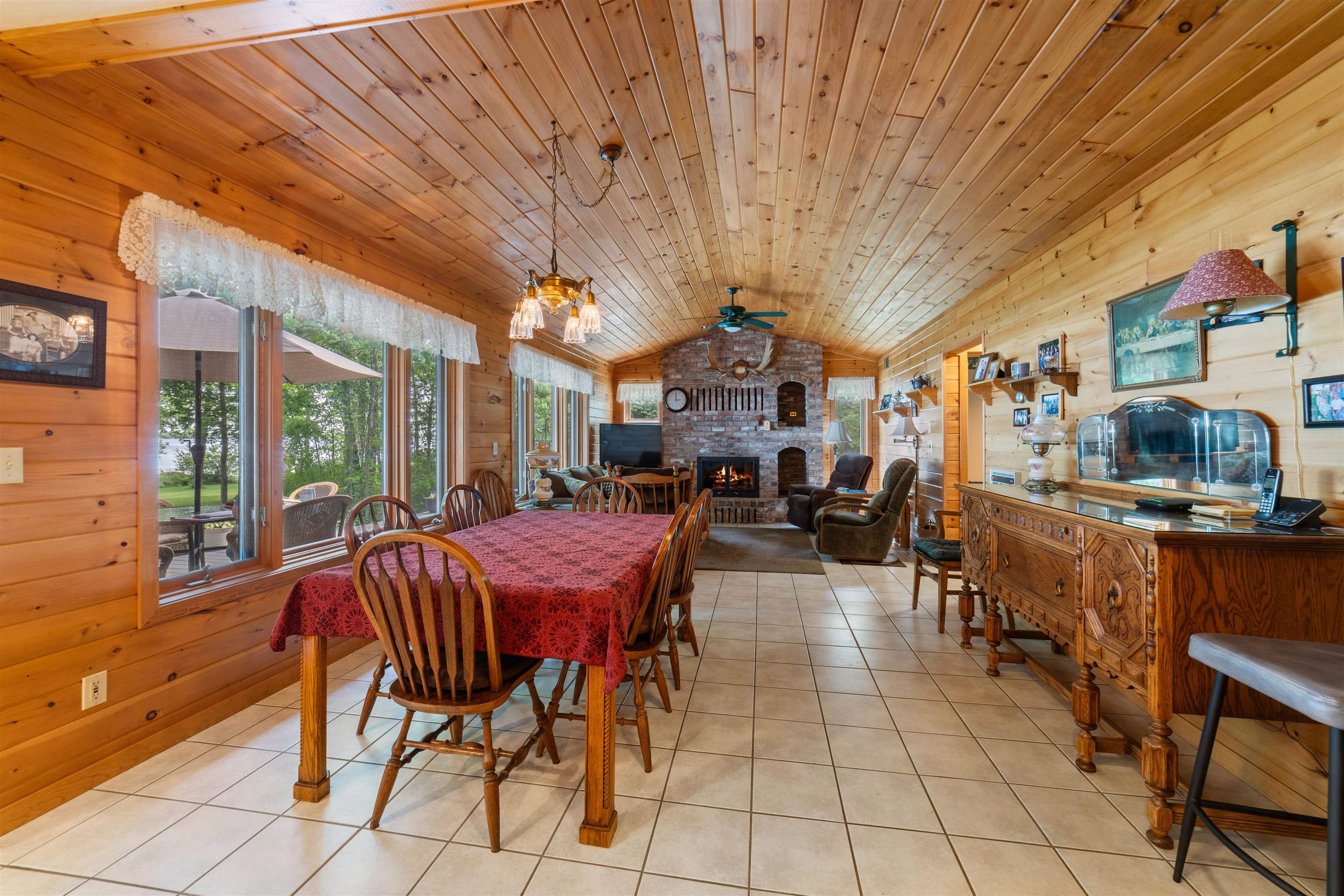 4930 Mini Power Road Duluth, MN 55803 - Photo 6 of 36 Dining room featuring wood walls, vaulted ceiling, a fireplace, light tile patterned floors, and a chandelier
