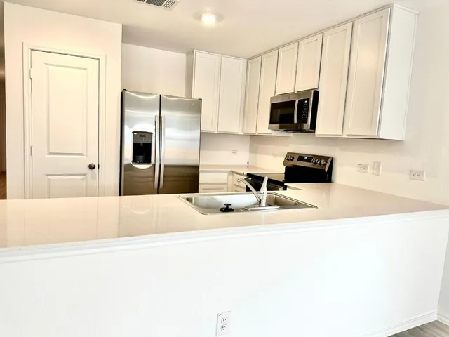 a kitchen with stainless steel appliances a stove a microwave a refrigerator a sink and dishwasher