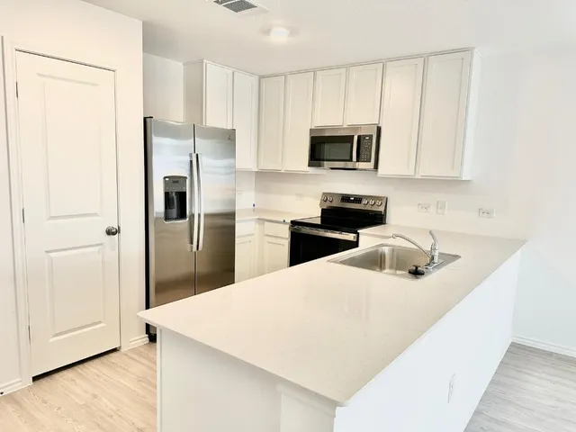 a kitchen with stainless steel appliances a microwave a sink a refrigerator and cabinets