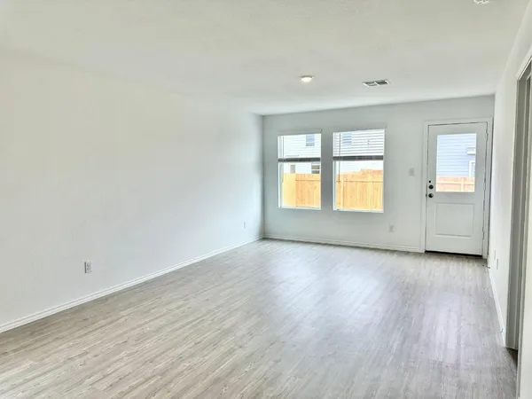 a view of an empty room with a window and wooden floor