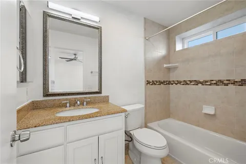 a bathroom with a granite countertop sink a toilet and shower