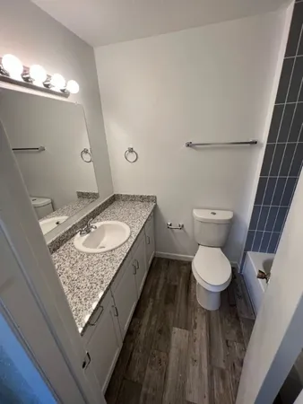 a bathroom with a granite countertop sink a toilet and a mirror